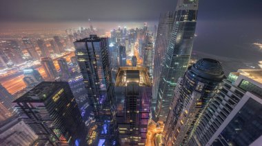 Dubai Marina 'nın ufuk çizgisi panoramik manzarası kıyı şeridi boyunca aydınlık gökdelenlerle çevrili kanalı gösteriyor. Gece gündüz geçiş zamanı. Güneş doğmadan önce sisli bir hava. Dubai, BAE