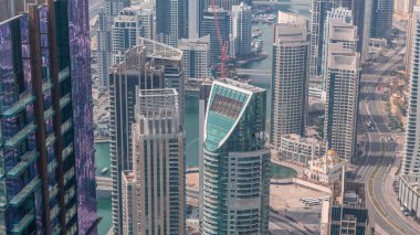 Dubai Marina 'nın Skyline manzarası kıyı şeridi boyunca gökdelenlerle çevrili yapay bir kanal gösteriyor. Rıhtım yakınında yüzen yatlar ve cami. Dubai, BAE