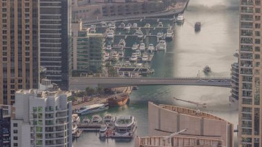 Dubai Marina kıyı şeridi boyunca gökdelenlerle çevrili yapay bir kanalı gösteriyor. Limanda yüzen yatlar ve tekneler. Dubai, BAE
