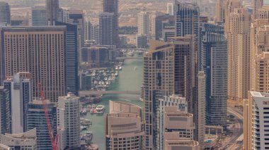 Dubai Marina 'nın gökdelenlerle çevrili bir yapay kanalı tüm gün boyunca gölgelerle hareket eden hava zaman çizelgesini gösteriyor. Yüzen yatlar ve tekneler. Dubai, BAE