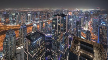 Panorama, Dubai Marina 'yı JLT ve JBR bölgesiyle gösteriyor. Gökdelenler arasındaki otoyolda trafik vardı. Hava gece zaman çizelgesi. Aydınlatılmış modern kuleler ve inşaat alanı