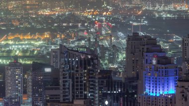 Dubai Marina 'nın gökdelenlerini gösteren gökdelenlerin panoramik görüntüsü. Arka planda tüten borular olan bir bitki. Dubai, BAE