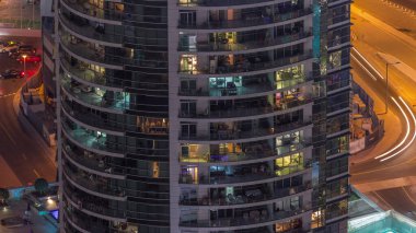 Modern kulelerin pencerelerinde ışık var. Geceleri parlayan pencereleri zaman ayarlı bir apartmanın dışında. Gökdelenin yukarıdan aydınlatmalı havadan görünüşü. Arabalar arkada.