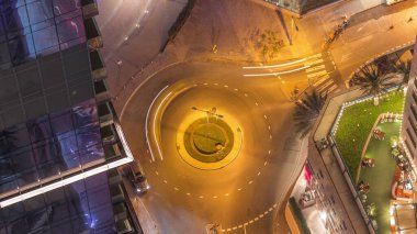 Gökdelenler arasındaki kavşağın havadan görünüşüne bakın. Büyük bir şehrin gece zaman diliminde. BAE 'nin Dubai Marina bölgesinin şehir manzarası ve kavşakta araba trafiği