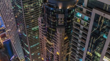 Gece manzarasına bakış açısı, lüks Dubai Marina gökdelenlerinin gece zaman çizelgesini vurguluyor. Parlayan pencereli kulelerin arkasındaki rıhtım, Dubai, Birleşik Arap Emirlikleri