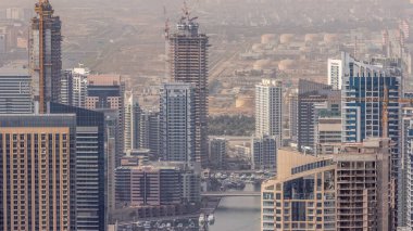 Dubai Marina 'nın Skyline panoramik görüntüsü kıyı şeridi boyunca gökdelenlerle çevrili yapay bir kanal gösteriyor. Vinçleri olan bir inşaat alanı. Dubai, BAE