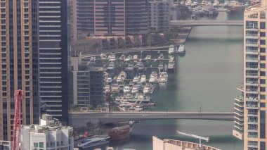 Dubai Marina 'nın kıyı şeridi boyunca gökdelenlerle çevrili yapay kanalların üzerindeki köprüyü gösteren yakın görüntüsü. Limandaki yatlar ve tekneler. Dubai, BAE