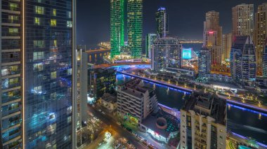 Dubai Marina gökdelenleri ve lüks binalarda parlayan camları olan JBR semti ve gece uçuşları için uygun zaman aralığı. Aydınlatılmış rıhtım ve kanalda yüzen tekneler