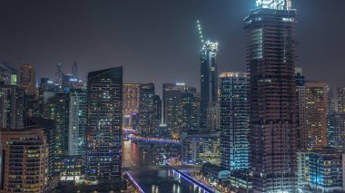 Dubai Marina 'da limana park etmiş birkaç tekne ve yatı var. Kanal havası çevresindeki gökdelenleri aydınlatıyorlar. İnşaat halindeki kuleler