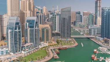 Dubai Marina 'da limana park etmiş birkaç tekne ve yatları ve kanalın etrafında gökdelenleri var. JBR bölgesinin gölgeleri hızla hareket ediyor.