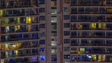 Dışarıdaki apartmanın gece manzarası renkli zaman çizelgesi. Pencere ve balkonlarında parlayan ışıklar olan yüksek gökdelen