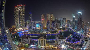 Dubai Marina Panoraması 'nda limana park edilmiş tekne ve yatlarla ve tüm gece boyunca kanalın çevresindeki gökdelenlerle aydınlandı. Arka planda JBR bölgesi kuleleri