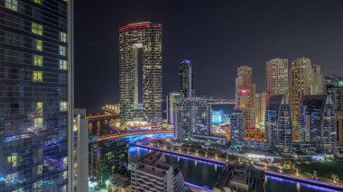 Dubai Marina gökdelenleri ve JBR semti. Lüks binalar ve otellerin zaman çizelgeleri var. Işıklar tüm gece kapalı. Aydınlatılmış rıhtım ve kanalda yüzen tekneler
