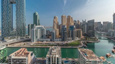 Dubai Marina Panorama 'sında limana park etmiş birkaç tekne ve yatlar ve kanalın etrafında gölgeli gökdelenler var. Arka planda JBR bölgesi kuleleri