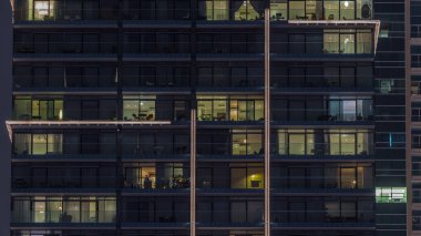 Çok katlı binaların panoramik pencerelerinde, çok renkli ışıktan oluşan düz bir panorama. Büyük bir şehirde aydınlık bir gökdelen.
