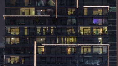 Çok katlı cam binaların panoramik pencerelerindeki çok renkli ışıkların düz gece panoraması. Büyük bir şehirde aydınlık bir gökdelen.