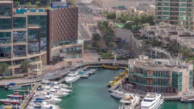 Dubai Marina 'da avuçiçi avuçlarla rıhtım gezintisi. Yatlar ve tekneler suyun üzerinde yüzüyor. Kavşağın yakınındaki kavşakta trafik vardı.