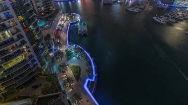 Dubai Marina hava sahasında palmiyelerle rıhtım gezintisi. Su taşıma istasyonuna bak. Yatlar ve tekneler suda yüzüyor.