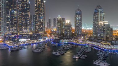 Dubai Marina turistik bölgesi, gökdelenleri ve kanalı çevreleyen kuleleri var. Parlak pencereli gizli binalar. Yatlar suda yüzüyor.