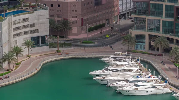 Dubai Marina 'da avuçiçi avuçlarla rıhtım gezintisi. Yatlar ve tekneler suyun üzerinde yüzüyor. Yolda trafik vardı.