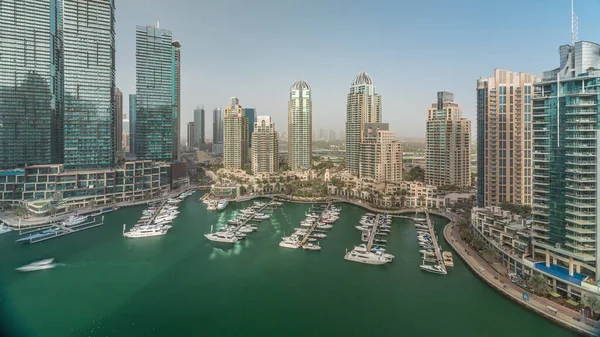 Gün batımında Dubai marinasında bulunan şehrin havadan seyretme panoramasında lüks yat hangarı. Rıhtım boyunca modern gökdelenler ve limanda yüzen tekneler.