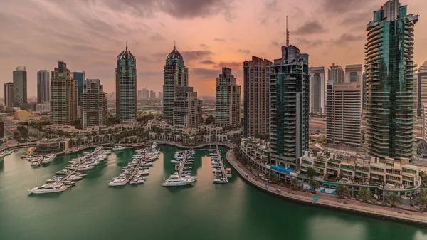 Dubai Marina turizm bölgesi üzerinde gündoğumu. Gökdelenler ve kanalın çevresindeki panoramik zaman çizelgeleri. Residential binalar ve caddelerdeki trafik