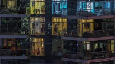 Çok katlı binaların pencerelerinde düz gece panoramasında çok renkli ışık var..