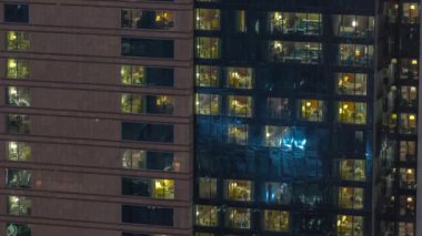 Gece vakti üst sınıf bir binanın pencerelerinin önünde pencereler var.