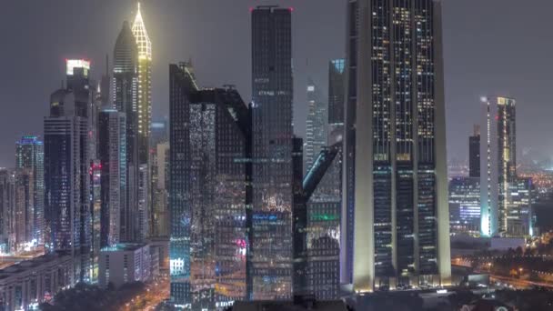 Close up view of Dubai Financial Center district with tall skyscrapers illuminated at night timelapse. — Stock Video