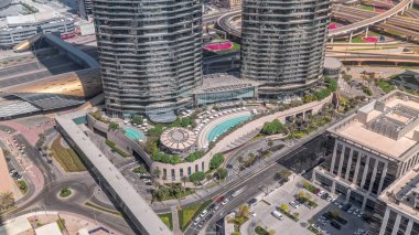 Dubai şehir merkezindeki otelin yakınındaki çatı yüzme havuzu. Beyaz şemsiyeler ve güneşlikler. Ofis binalarının yakınındaki bir yolda trafik vardı.