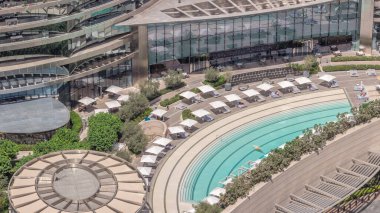 Çatıdaki çatıda yüzme havuzu ve şehrin havadan izlediği zaman dilimi. Beyaz şemsiyeler ve güneşlikler. Dubai, BAE