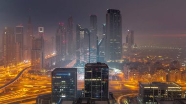 Dubai Finansal Merkezi 'nin panoraması. Gece gündüz aydınlatma saatleri olan yüksek gökdelenleri var. Güneş doğmadan önce sabah sisi olan kulelerin hava görüntüsü