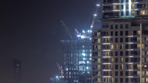 Tall buildings under construction and cranes night timelapse — Stok Video