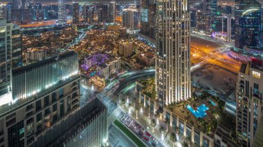 Gece vakti otelleri olan büyük, fütürist bir şehrin havadan panoramik görüntüsü. Dubai, Birleşik Arap Emirlikleri 'nin gökdelenleri ve geleneksel evleri olan iş sahası ve şehir merkezi..
