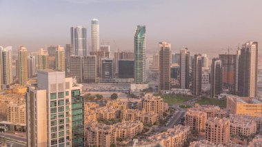 Akşam sıcacık ışıkta büyük, fütüristik bir şehrin panoramik silueti. Gökdelenleri ve geleneksel evleri olan iş sahası ve şehir merkezi bölgesi, Dubai, Birleşik Arap Emirlikleri