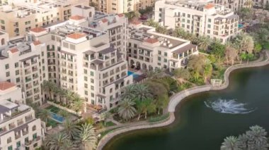 Yeşiller bölgesinde göleti ve çeşmesi olan alçak katlı binalar. Dubai silueti