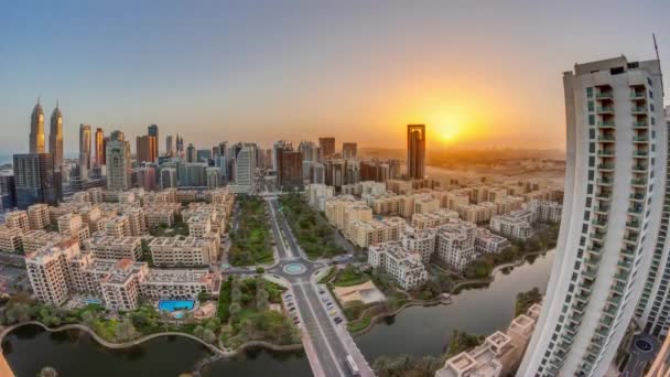 Salida del sol sobre rascacielos en el distrito de Barsha Heights y edificios de poca altura en el timelapse aéreo del distrito de Greens. — Vídeo de stock
