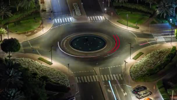 Движение на пересечении дорог с кольцевой развязкой в зеленом районе воздушной ночью Timelapse. — стоковое видео