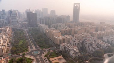 Barsha Heights bölgesindeki gökdelenler ve Greenens bölgesindeki alçak binalar. Dubai silueti tüm gün boyunca gölgeler hızla ilerlerken. Sokaklarda palmiyeler ve ağaçlar