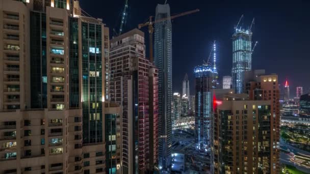 新しい高層ビルの大規模な建設現場で働くクレーン夜のタイムラプス — ストック動画