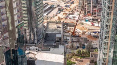 Crane ve buldozer yeni gökdelen hava zaman çizelgesinin şantiyesinde çalışıyorlar. Arazi temizliği, not verme, havuz kazma, siper kazma ve temel kazma. Sürüngen traktörü ve yer değiştirme ekipmanları