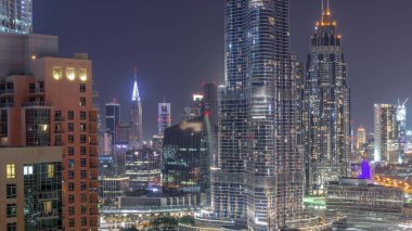 Şehir merkezinden tüm gece boyunca Dubai Uluslararası Finans Merkezi 'nin gökdelenlerinin hava görüntüsü. Aydınlatma kapalı camdan ofis kuleleri