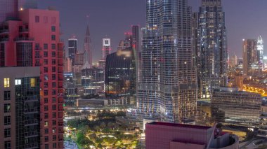 Dubai Uluslararası Finans Merkezi 'nin gökdelenleri gece gündüz şehir merkezinden geçiş zamanlarını gösteriyor. Camdan ofis kuleleri ve modern binaları olan oteller.