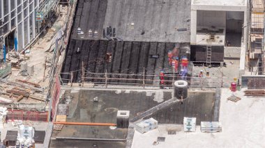 Yeni gökdelenin şantiyesinde çalışan işçiler çatıları, havadaki malzemelerle kaplıyorlar. Arazi temizliği, not verme, havuz kazma, siper kazma ve temel kazma. Sürüngen traktörü ve yer değiştirme ekipmanları