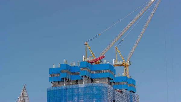 在新摩天大楼的大收缩工地上工作的起重机与蓝天相映成趣 高层塔楼的城市发展和建筑活动 — 图库照片