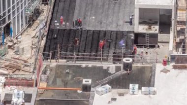 Yeni gökdelenin şantiyesinde çalışan işçiler, çatıdaki malzemelerin zamanlaması ile çatıları kapatıyor.