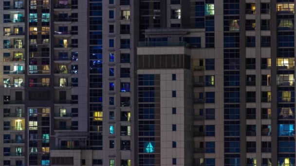 Lägenhet fönster av en glaserad skyskrapa glöd på natten med stadens ljus reflektion antenn timelapse. — Stockvideo