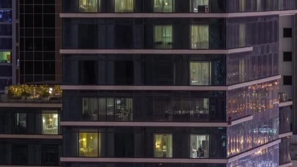 Apartman ablakai egy mázas felhőkarcoló világít éjjel városi fények visszaverődés légi időelapszus. — Stock videók