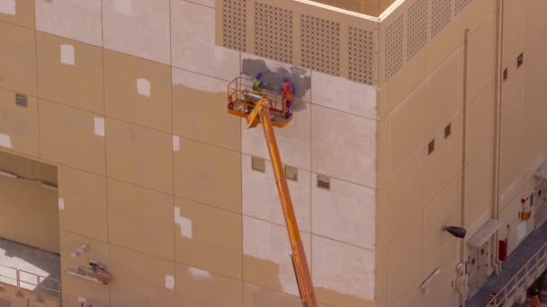Trabajadores de la construcción en cubo de vehículo grúa para la restauración y reparación de la fachada del timelapse aéreo del edificio. — Vídeos de Stock