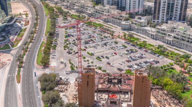 İş merkezinin park alanındaki arabaların hava manzarası, inşaat alanının yakınındaki tüm gün boyunca arabalı alışveriş merkezleri ve boş park yerleri. Gölgeler hızlı hareket ediyor